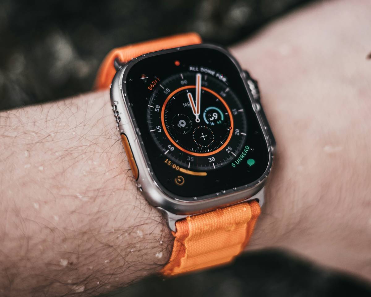 Hiker checking wristwatch altimeter display while standing on mountain ridge, illustrating interpreting altimeter data while hiking