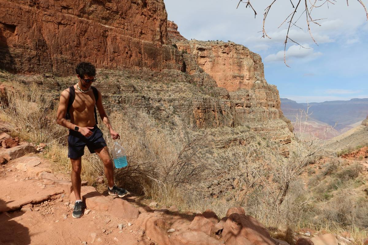 Hiker checking altimeter watch battery life on hikes while standing on mountain ridge